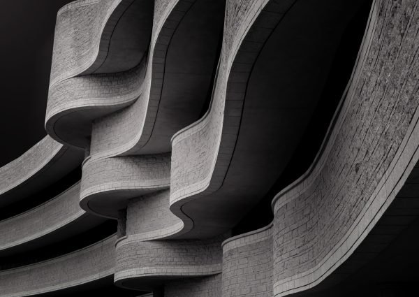 A low angle greyscale of a building with modern brutalist architecture under the sunlight